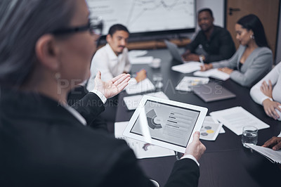 Buy stock photo Shot of a mature businesswoman using a digital tablet during a business meeting