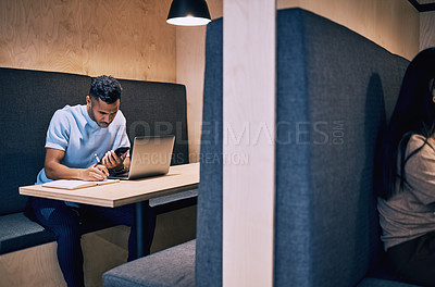 Buy stock photo Shot of a young businessman using a smartphone and laptop while working