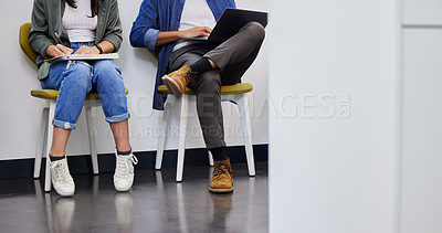 Buy stock photo Shot of two unrecognizable people using their devices while waiting to be interviewed in a modern office