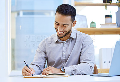 Buy stock photo Shot of a businessman making notes while sitting at his desk