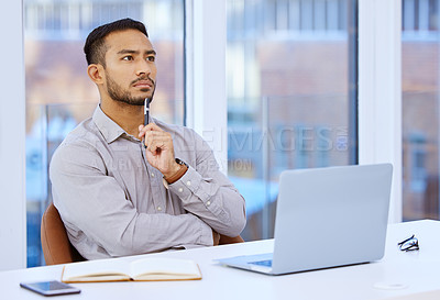 Buy stock photo Shot of a young businessman looking thoughtful while sitting at his desk