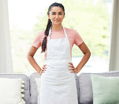 Buy stock photo Shot of a young woman wearing an apron while busy cleaning at home