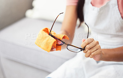 Buy stock photo Cropped shot of a woman cleaning her glasses while sitting at home