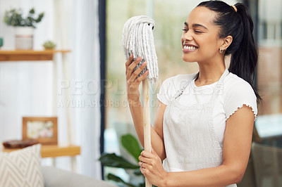 Buy stock photo Shot of a happy young woman holding a mop in her living room at home
