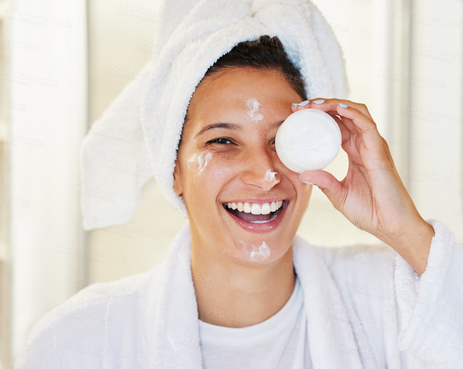 Buy stock photo Shot of a happy young woman holding up face cream