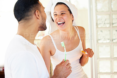Buy stock photo Shot of a happy young couple brushing their teeth in the bathroom at home