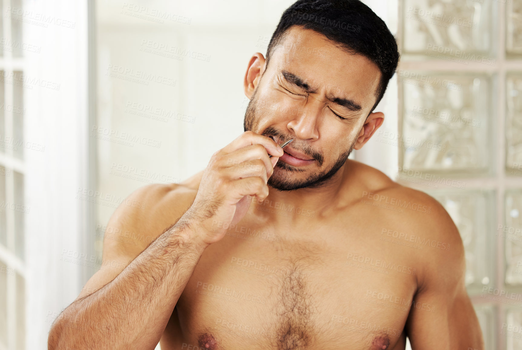 Buy stock photo Cropped shot of a young man using tweezers to pluck his nose hair
