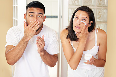 Buy stock photo Shot of a young couple moisturising their skin at home