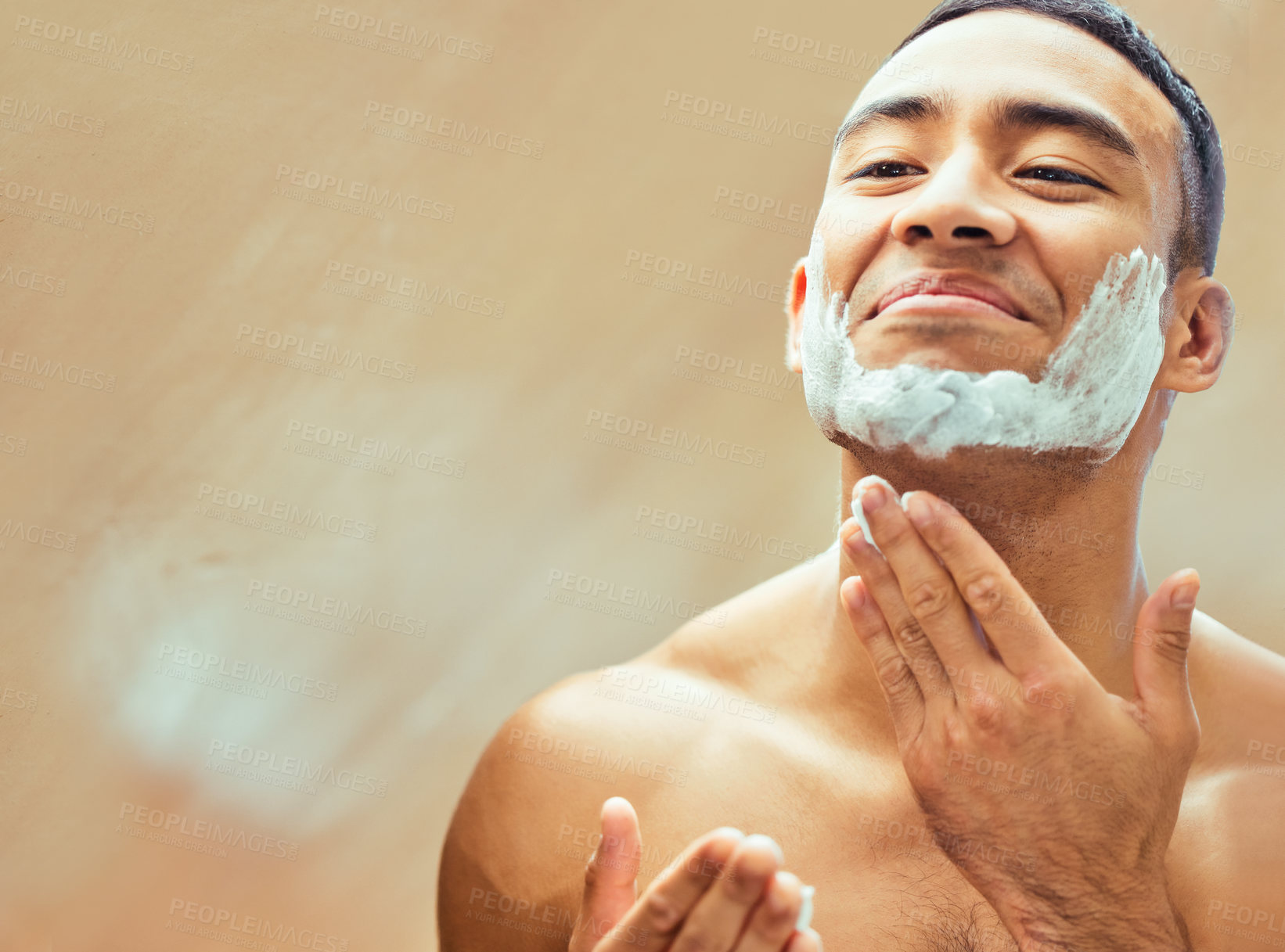 Buy stock photo Shot of a handsome young man applying shaving cream to his face