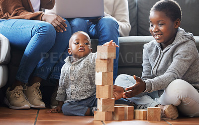 Buy stock photo Shot of a sister helping her baby brother build blocks in the lounge at home