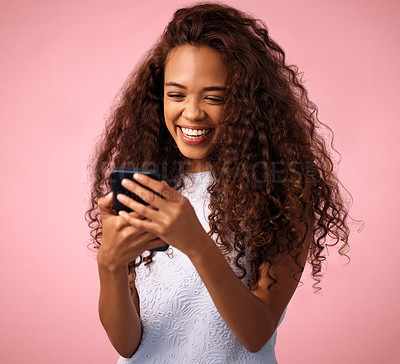 Buy stock photo Studio shot of a beautiful young woman using her cellphone while standing against a pink background