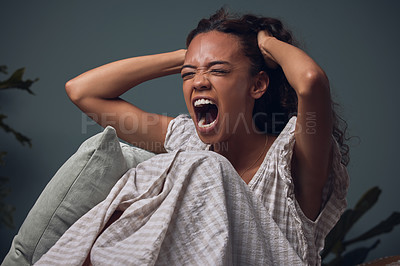 Buy stock photo Shot of a young woman screaming while sitting at home alone