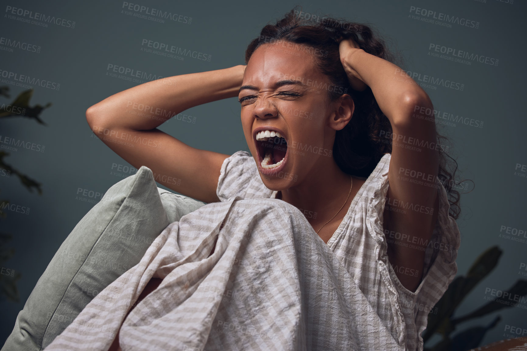 Buy stock photo Shot of a young woman screaming while sitting at home alone