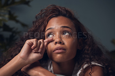 Buy stock photo Closeup shot of a young woman wiping her tears while sitting at home