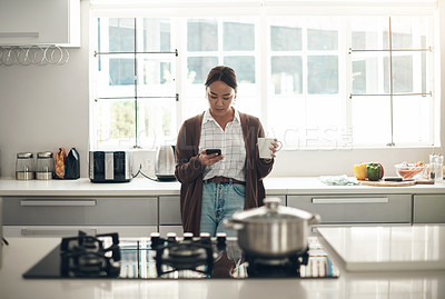 Buy stock photo Phone, coffee and woman in kitchen networking on mobile app, website or internet at apartment. Cappuccino, technology and young Asian female person scroll on cellphone in morning at modern home.