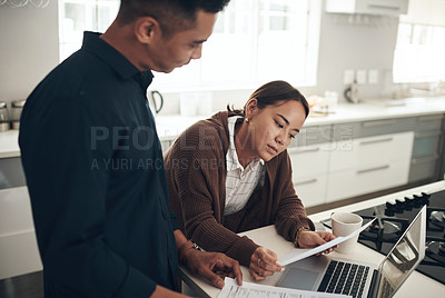 Buy stock photo Shot of a young couple going through paperwork while using a laptop at home