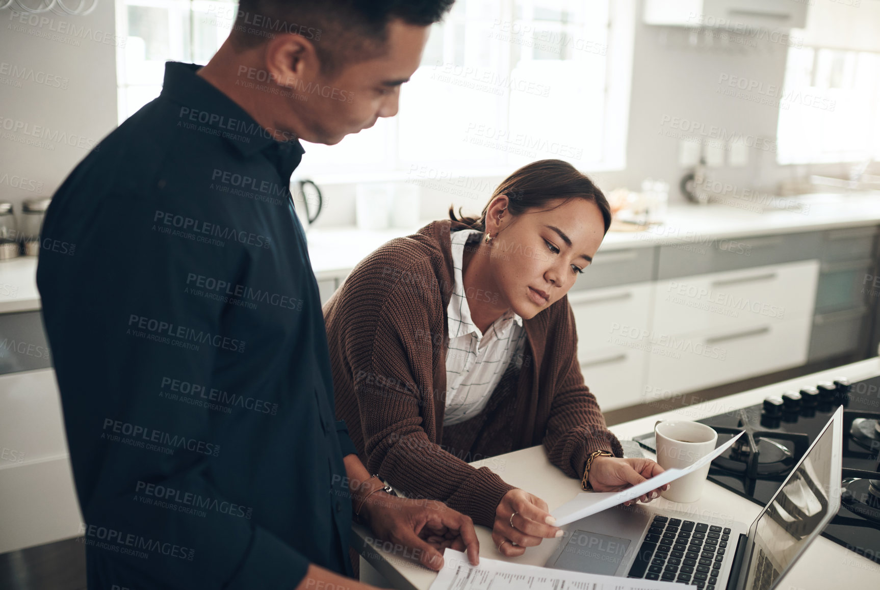 Buy stock photo Shot of a young couple going through paperwork while using a laptop at home