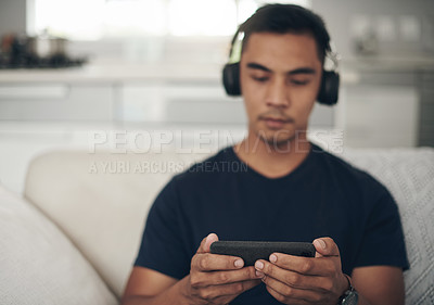 Buy stock photo Gaming, phone and relax with man on sofa in living room of home for competitive esports online. Communication, internet and technology with confident young person playing mobile game in apartment