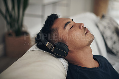 Buy stock photo Music, headphones and man relax on sofa listening to track, audio and radio in living room at home. Wellness, weekend and face of male with eyes closed streaming song for sleeping, calm or peace