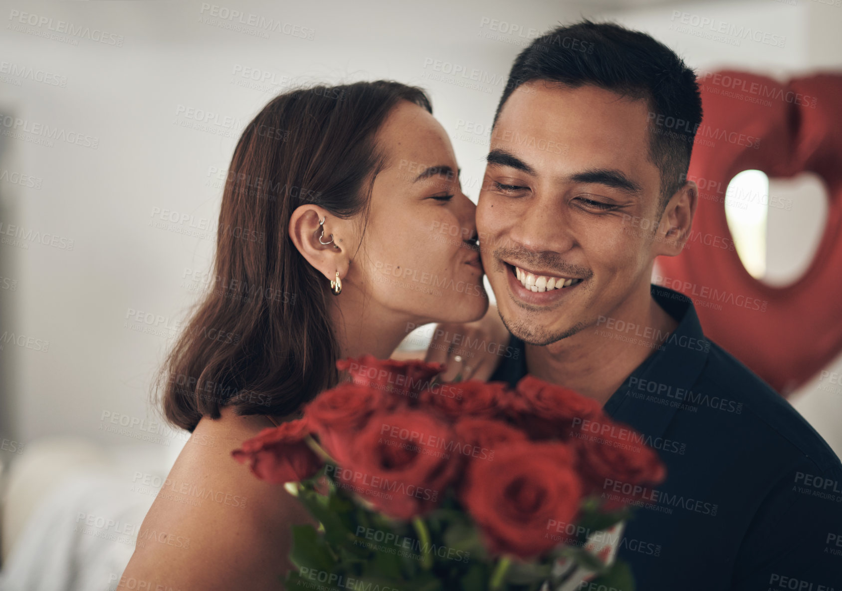 Buy stock photo Love, flowers and valentines day with a couple kissing in their home, in celebration of romance. Dating, rose bouquet or surprise with a man and woman in a house to kiss while bonding in intimacy