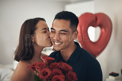 Buy stock photo Love, roses and valentines day with a couple kissing in their home, in celebration of romance. Dating, flower boquet or surprise with a man and woman in a house to kiss while bonding in intimacy