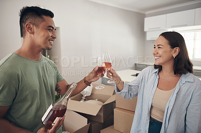 Buy stock photo Shot of a young couple sharing a toast in their new home