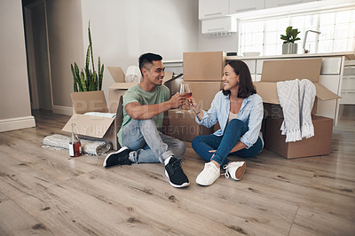 Buy stock photo Shot of a young couple sharing a toast in their new home