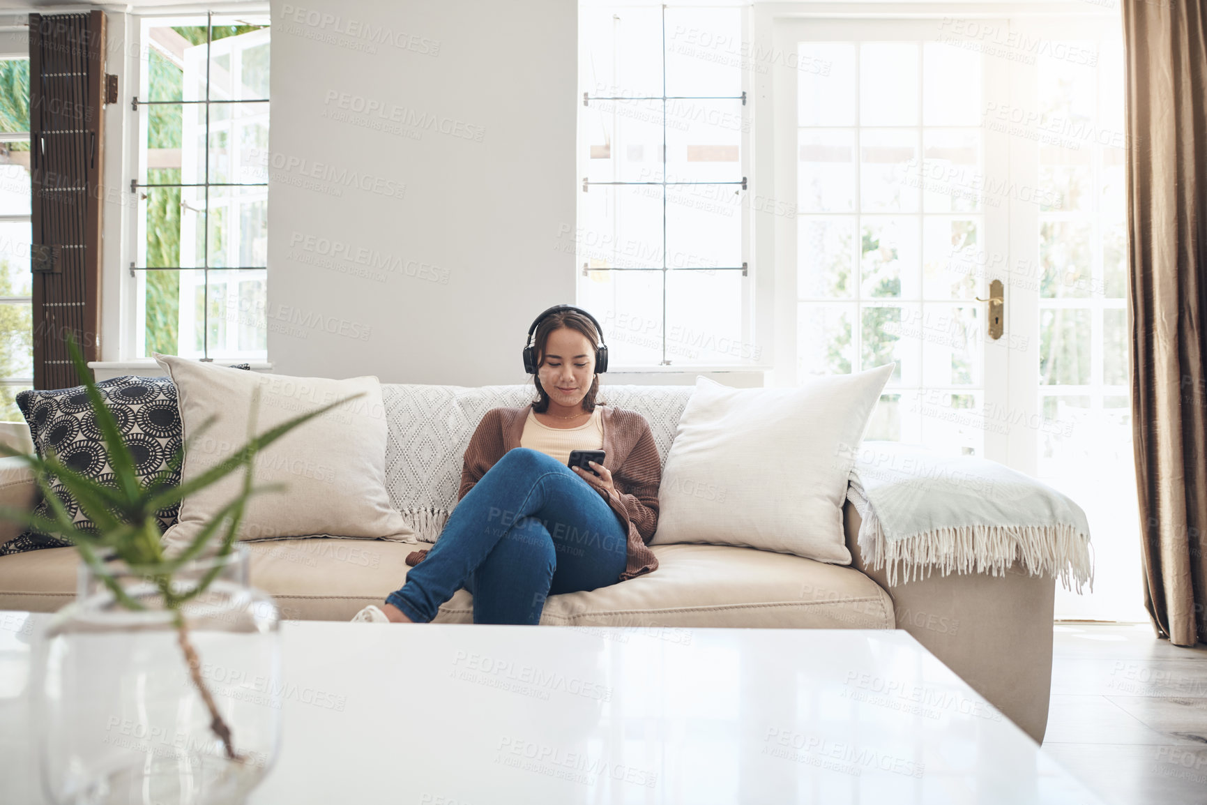 Buy stock photo Woman, headphones and phone for social media on couch, internet and music to relax in home. Female person, online and streaming movie or gossip article and song, reading and ebook or app for chat