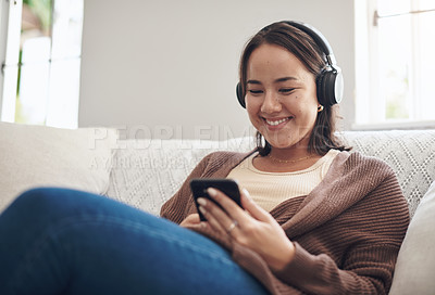 Buy stock photo Happy woman, headphones and listening with phone to music on sofa for audio streaming or weekend at home. Female person with smile, relax or enjoying sound track on mobile smartphone in living room