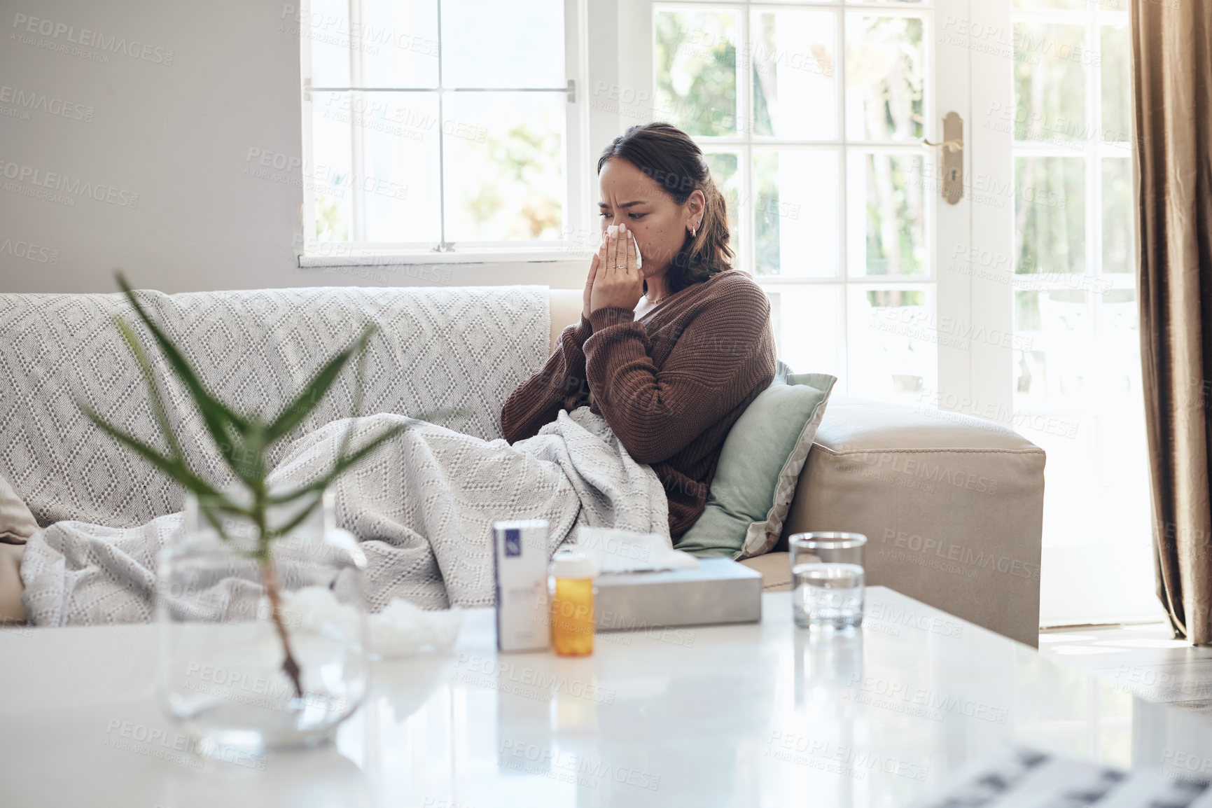 Buy stock photo Sick woman, tissue and blowing nose with flu, cold or illness on living room sofa at home. Young female person with medication for sneeze, fever or influenza from infection on lounge couch at house