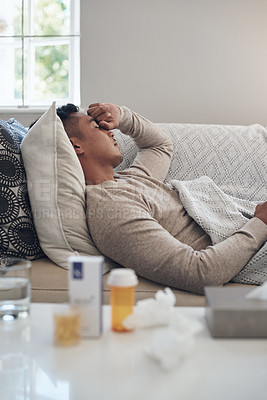 Buy stock photo Shot of a young man experiencing a headache while feeling sick at home