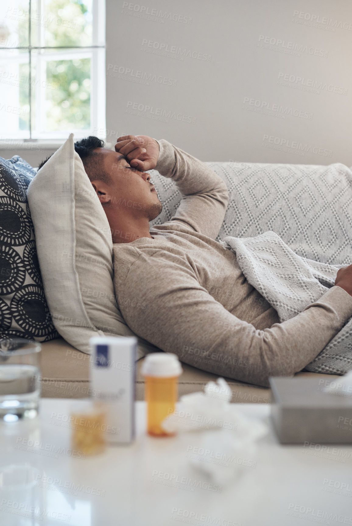 Buy stock photo Shot of a young man experiencing a headache while feeling sick at home