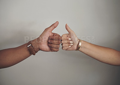 Buy stock photo Cropped shot of an unrecognizable couple standing together against a grey wall indoors and making a thumbs up hand gesture