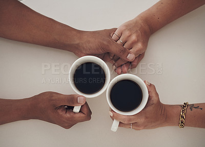 Buy stock photo High angle shot of an unrecognizable couple sitting together and enjoying a cup of coffee while holding hands