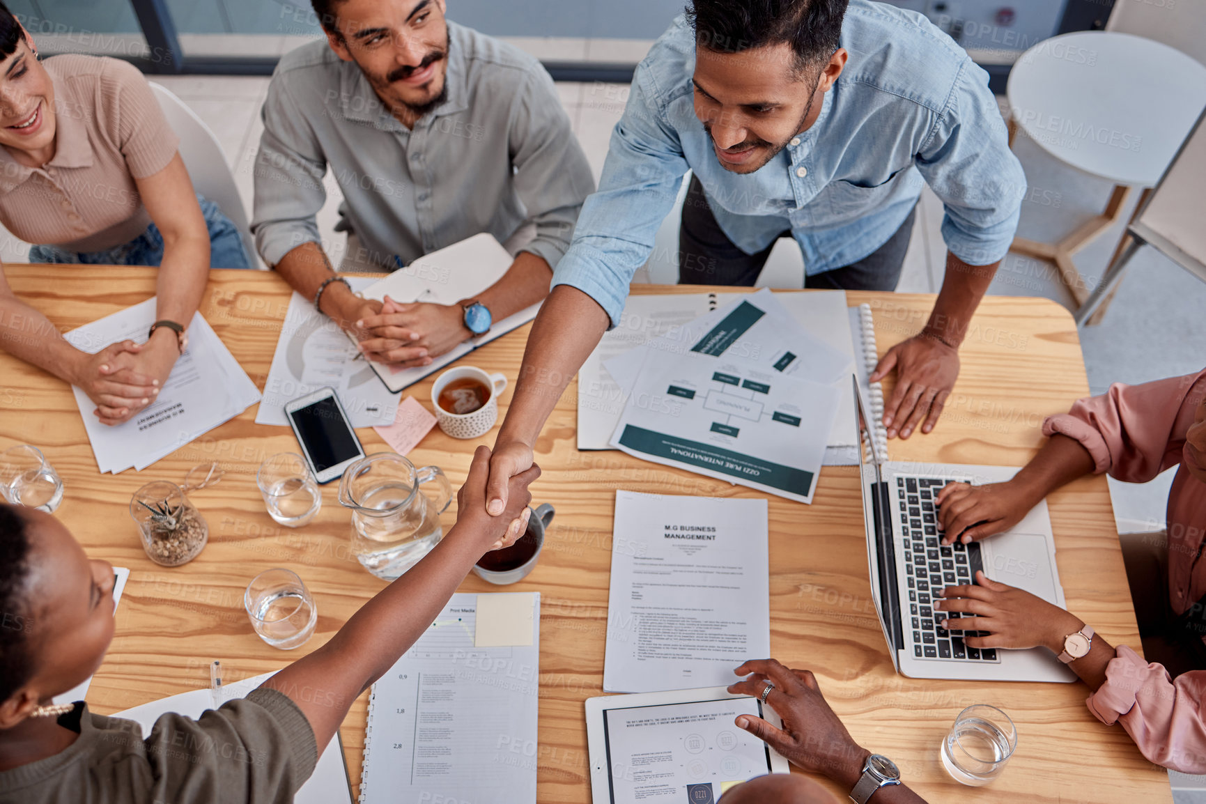 Buy stock photo Business people, handshake and meeting with documents for deal, agreement or partnership above at office. Top view of businessman shaking hands for teamwork, b2b or thank you for hiring at workplace