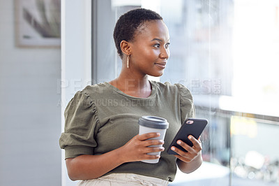 Buy stock photo Shot of a businesswoman drinking coffee and using her cellphone while looking out her office window