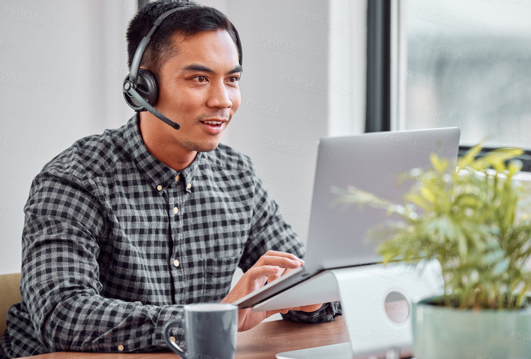 Buy stock photo Cropped shot of a handsome young male call center agent working on his laptop