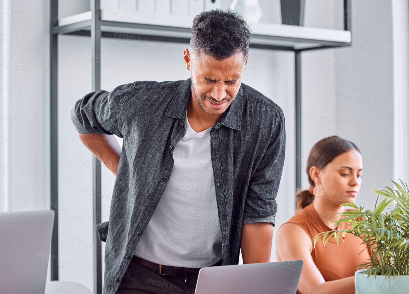 Buy stock photo Office, desk and man with back pain, laptop and burnout in coworking space or design agency. Stress, posture and creative businessman with spine pressure, overworked or fatigue at professional job