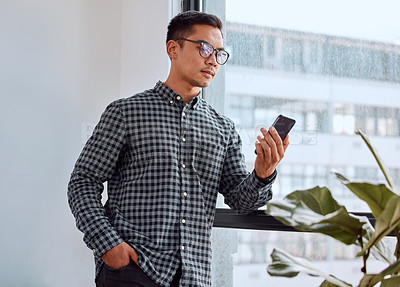 Buy stock photo Shot of a young businessman using a phone in an office