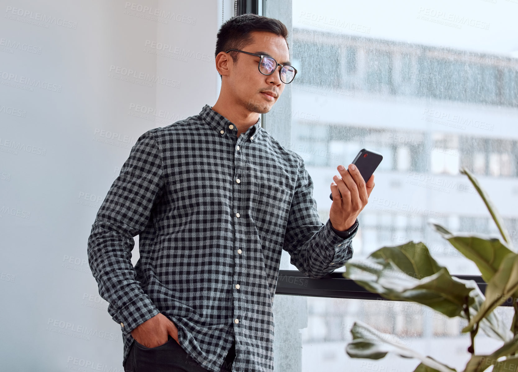 Buy stock photo Shot of a young businessman using a phone in an office