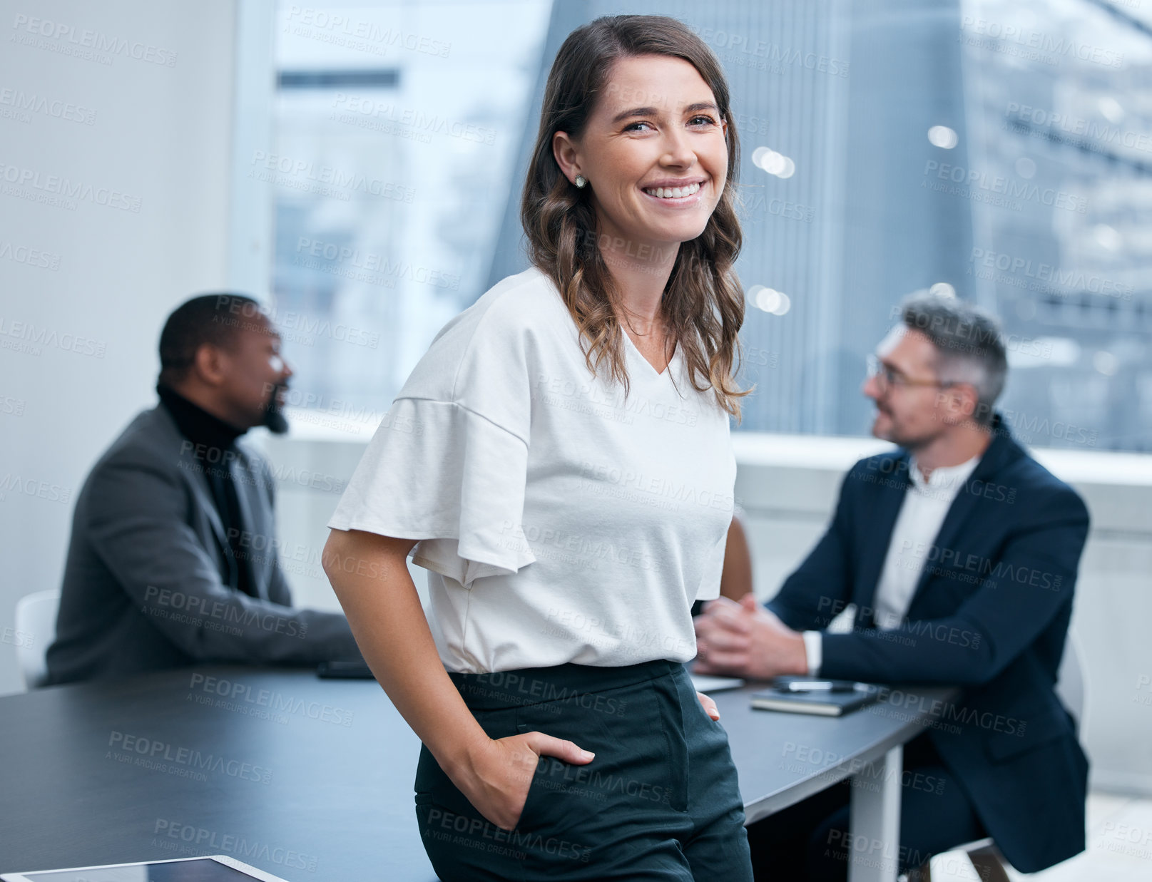 Buy stock photo Portrait of a confident young businesswoman standing in an office with her colleagues in the background