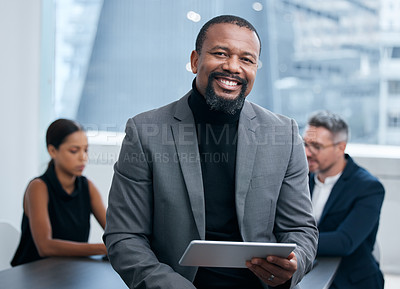 Buy stock photo Portrait of a mature businessman using a digital tablet in an office with his colleagues in the background