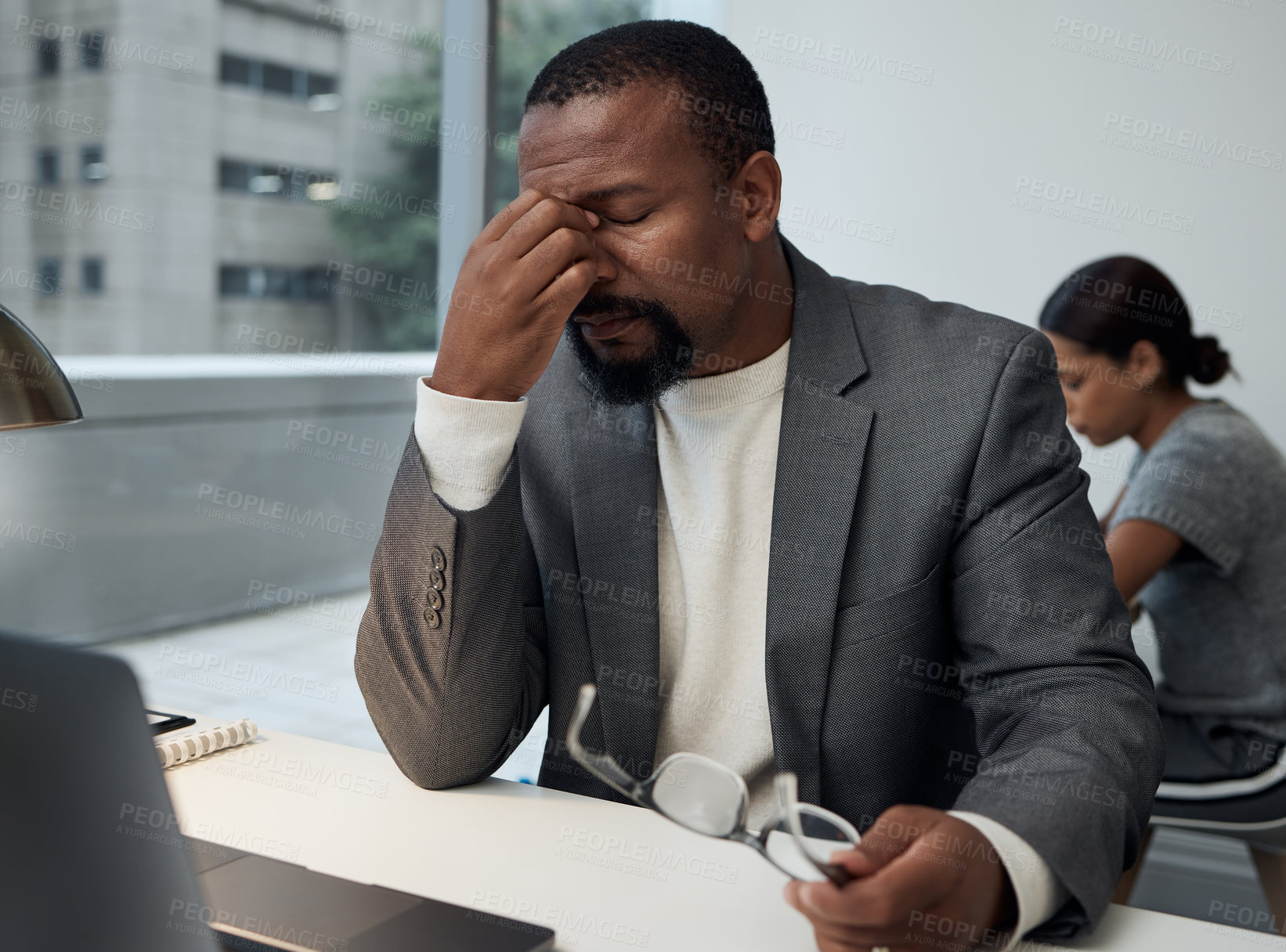 Buy stock photo Shot of a young businessman experiencing a headache at work