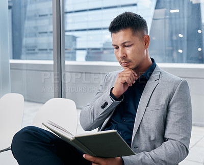 Buy stock photo Shot of a young businessman reading a book in a waiting room