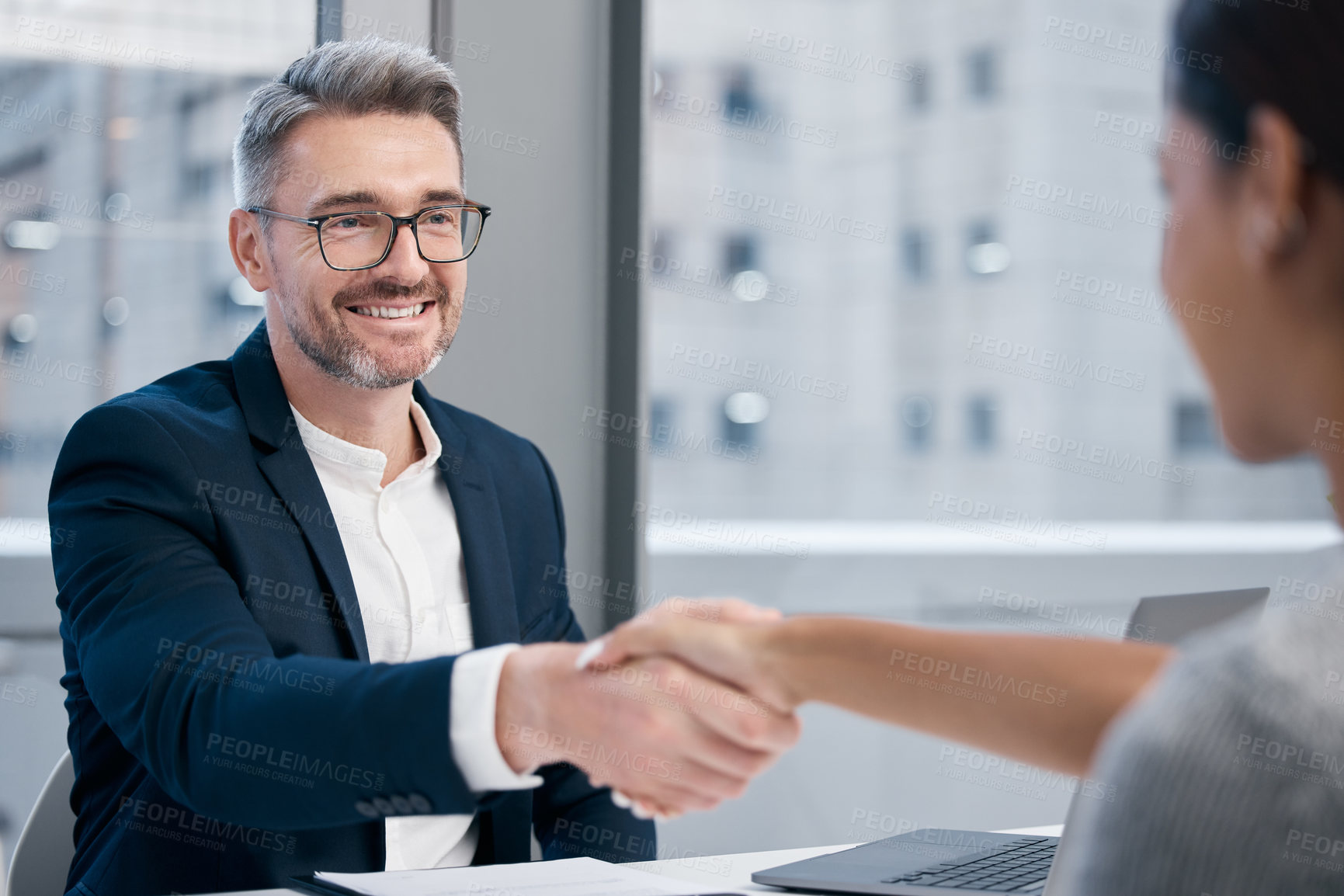 Buy stock photo Shot of two businesspeople shaking hands in an office