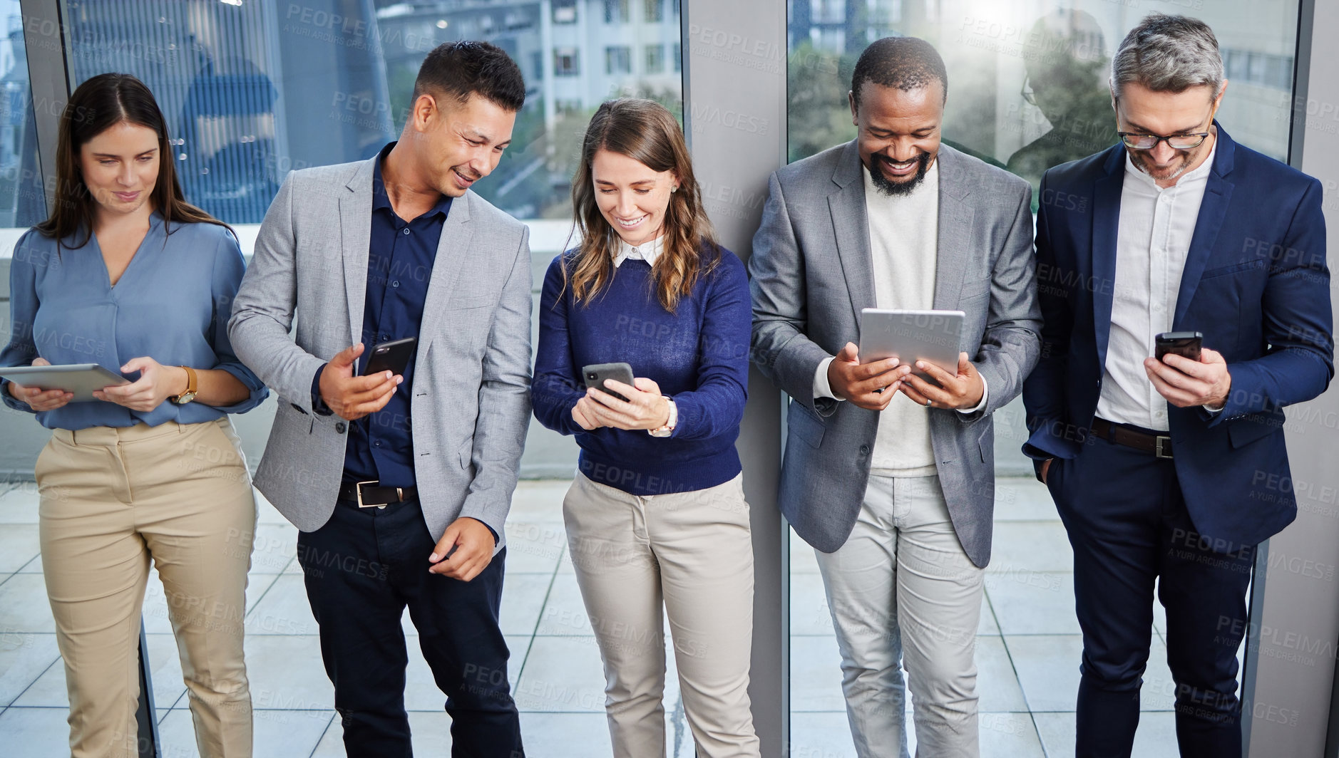 Buy stock photo Shot of a group of young businesspeople using digital devices while waiting in line