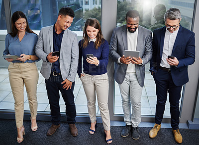 Buy stock photo Shot of a group of young businesspeople using digital devices while waiting in line