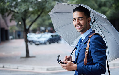 Buy stock photo Cropped portrait of a handsome young businessman with an umbrella on his morning commute into work