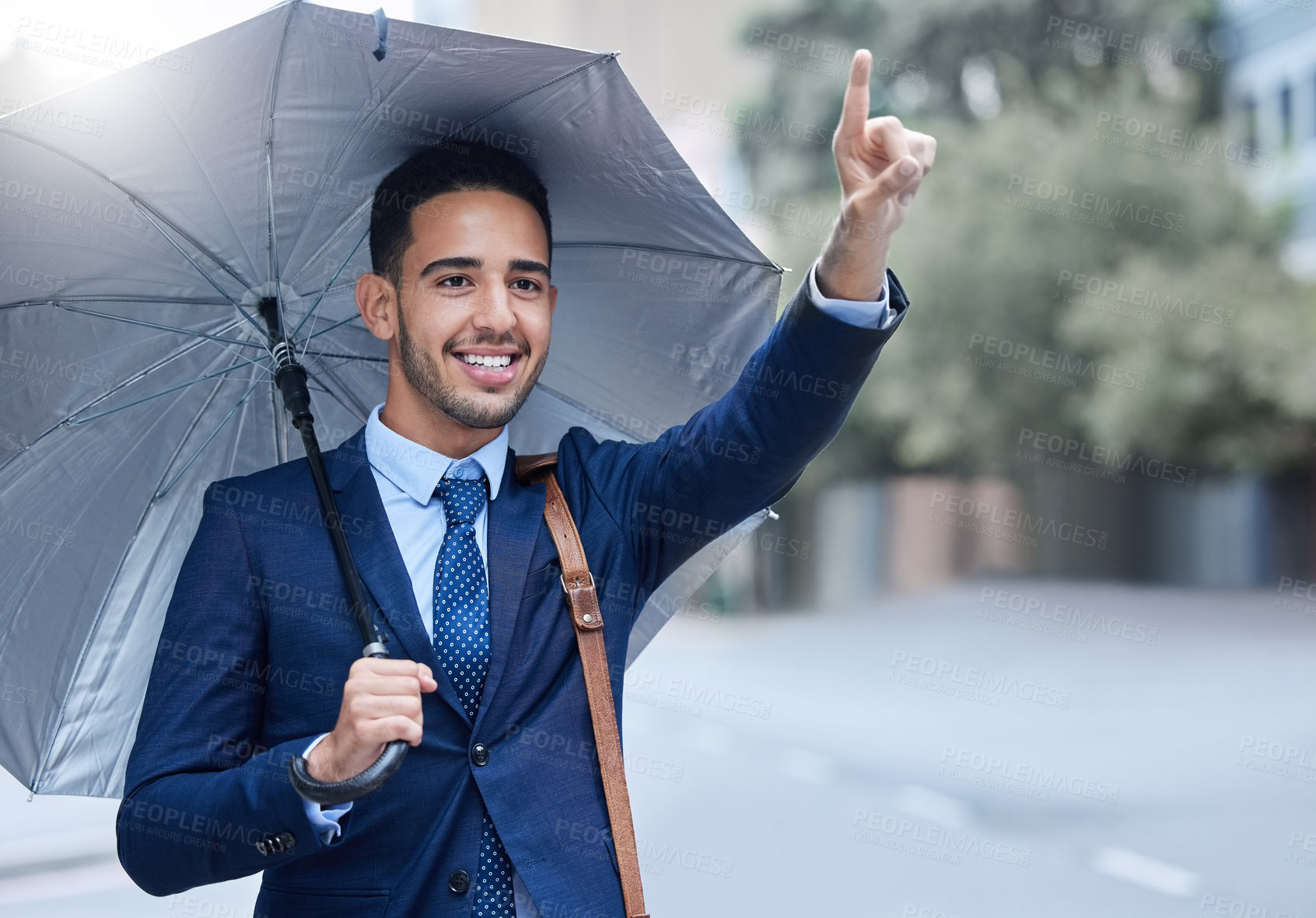 Buy stock photo Cropped shot of a handsome young businessman with an umbrella hailing a cab while on his morning commute into work