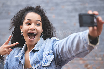 Buy stock photo Shot of a beautiful young woman using her cellphone to take a selfie outside